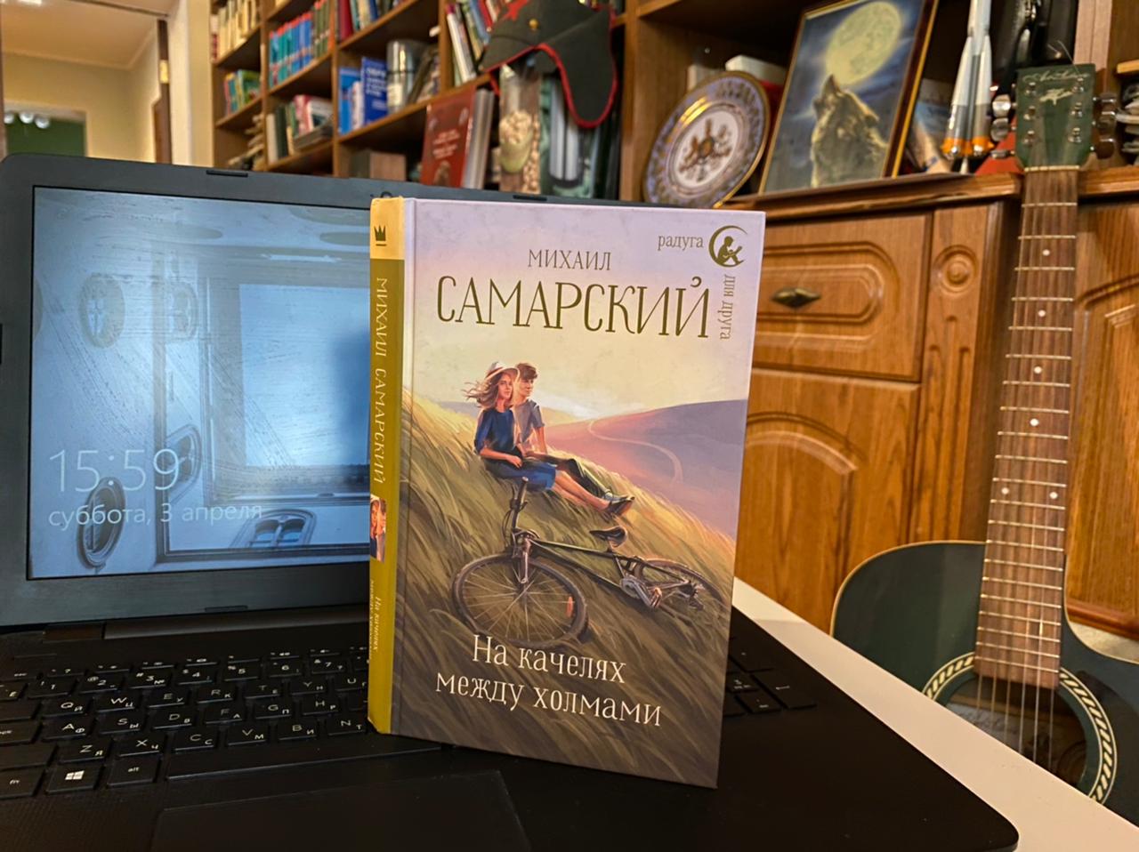 Photograph of the authentic published book On the Swings Between the Hills by Mikhail Samarsky, showing two young people on a grassy hillside with a bicycle